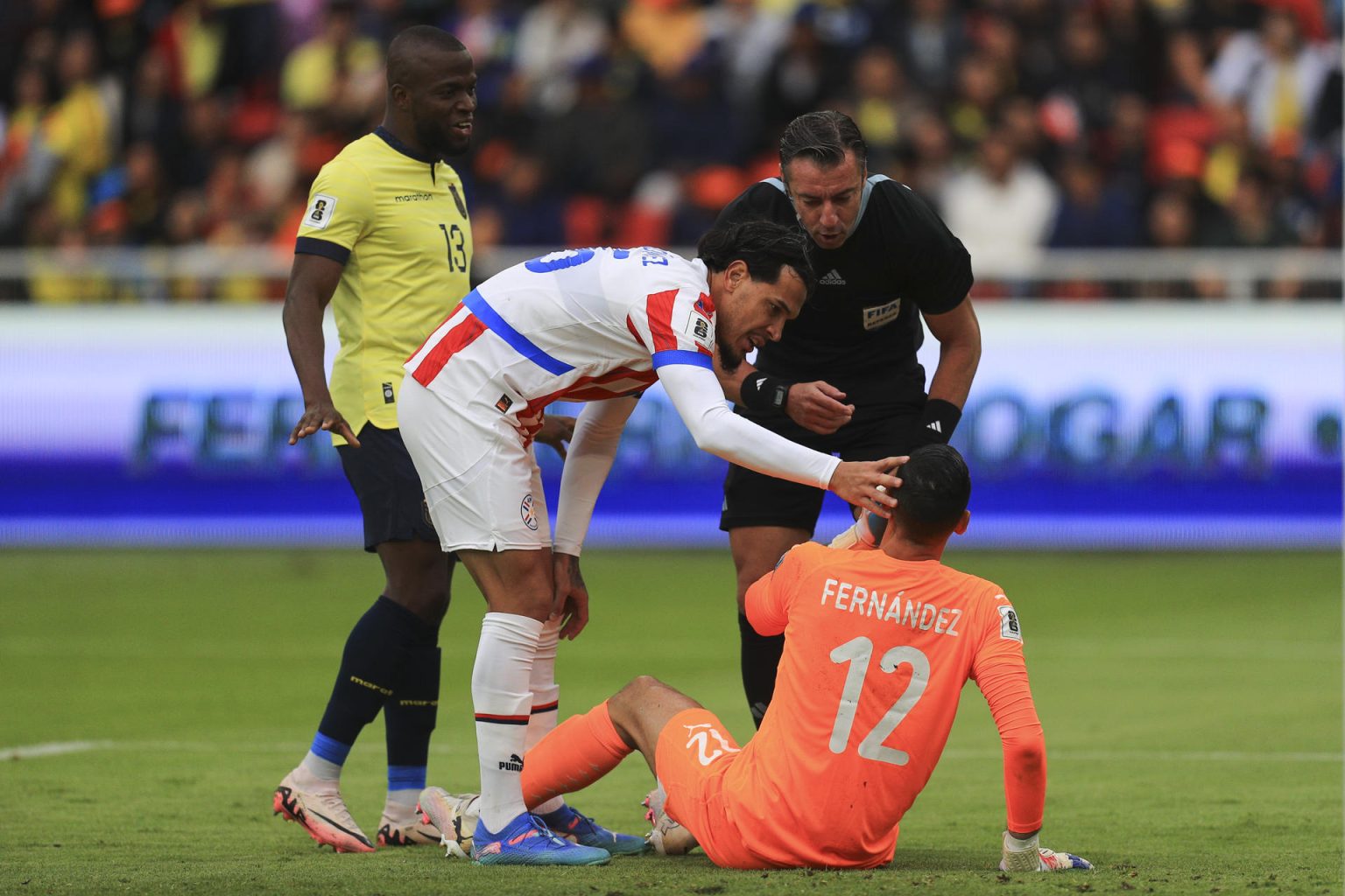 Roberto Junior Fernández (abajo) portero de Paraguay recibe atención luego de una falta en un partido de las eliminatorias sudamericanas para el Mundial de 2026. EFE/ José Jácome