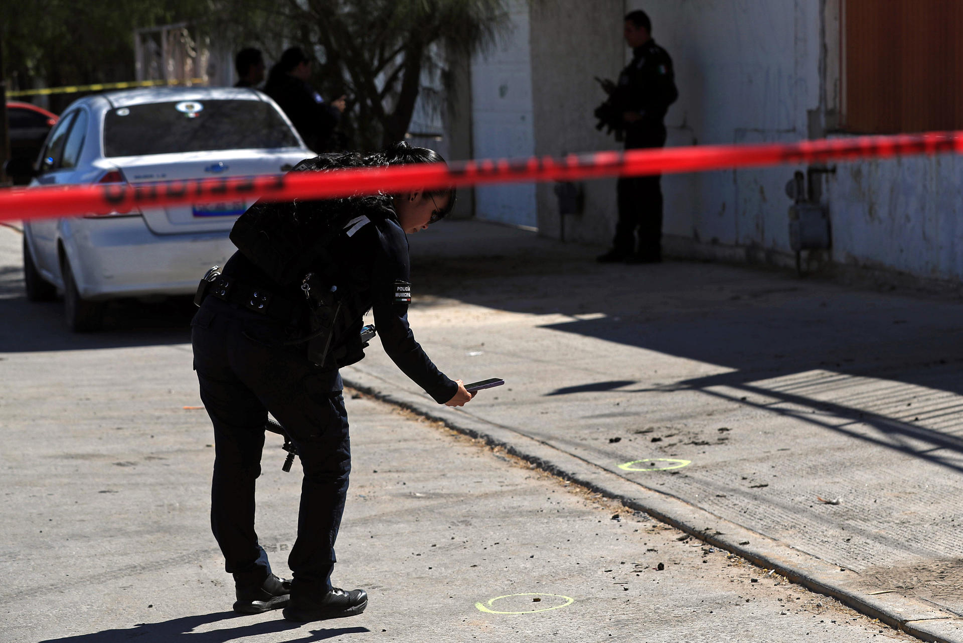 Una policía estatal toma una fotografía de un casquillo en el área donde se cometió un crimen este lunes en Ciudad Juárez (México). EFE/ Luis Torres.
