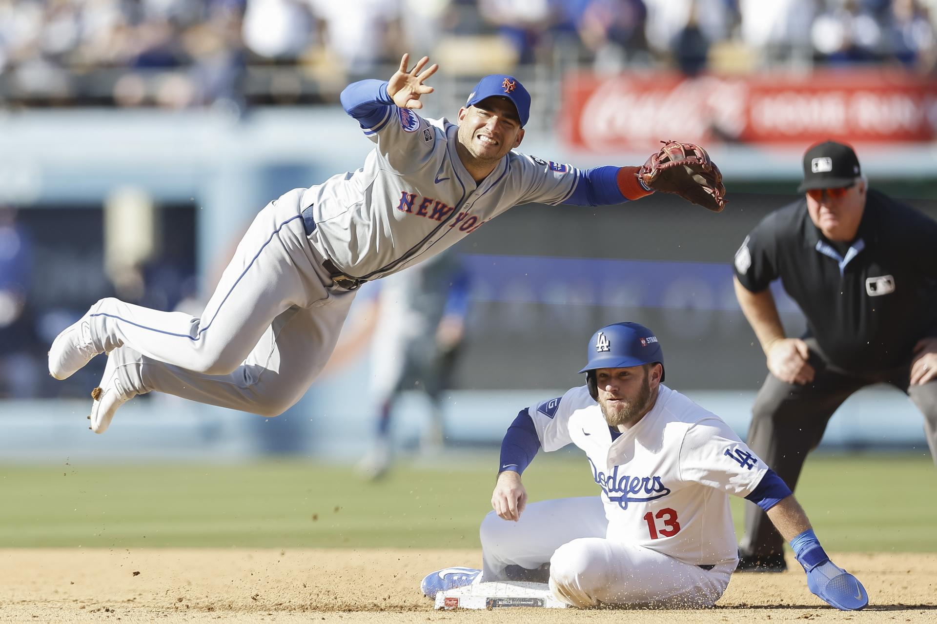 José Iglesias (i) de los Mets logra un doble play sobre Max Muncy (centro) de los Dodgers este lunes durante el segundo juego de la Serie de la Liga Nacional de Grandes Ligas en Los Ángeles. EFE/EPA/CAROLINE BREHMAN
