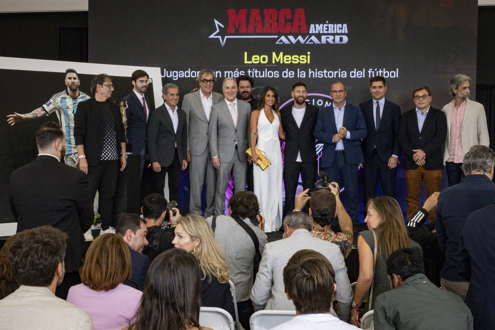 El jugador argentino Lionel Messi y su esposa Antonella Roccuzzo (c), posan rodeados por los directivos de Marca, del club Inter Miami y otros invitados, durante la ceremonia de entrega del Premio Marca América, este jueves en el Estadio Chase en Fort Lauderdale, Florida (Estados Unidos). EFE/Eva Marie Uzcátegui
