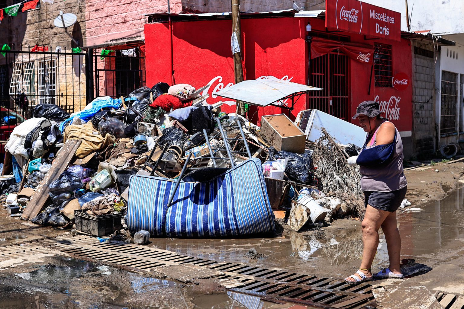 Una persona camina entre basura y enseres domésticos abandonados este lunes en las calles de la unidad habitacional Colosio, una de las más afectadas tras el paso del huracán John, en el balneario de Acapulco (México). EFE/David Guzmán