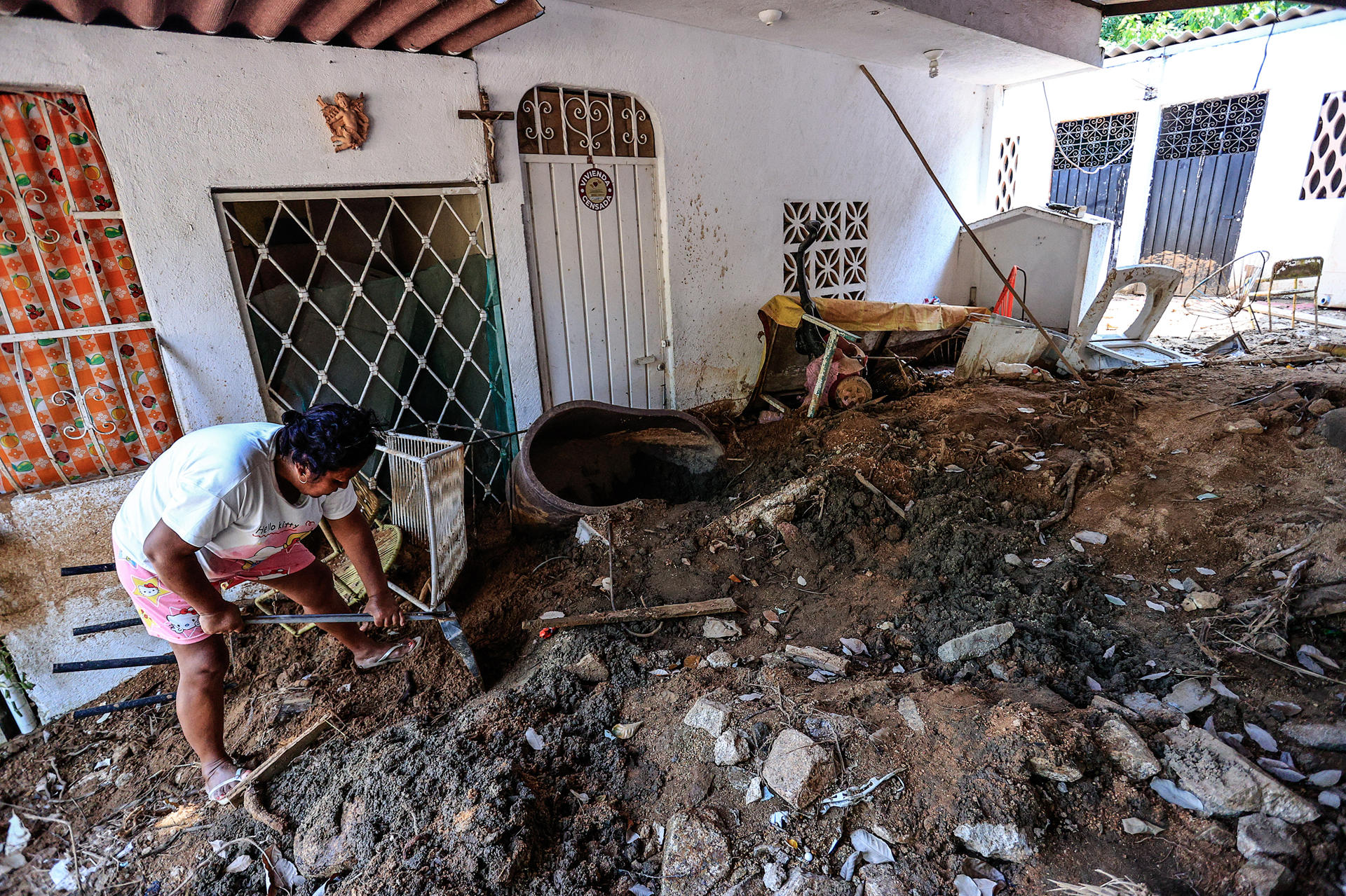 Fotografía aérea del 16 de octubre de 2024 de una mujer retirando tierra en una de las casa afectadas, en colonia Ampliación Libertad, tras el paso del huracán 'John', en el balneario de Acapulco en el estado de Guerrero (México). EFE/David Guzmán
