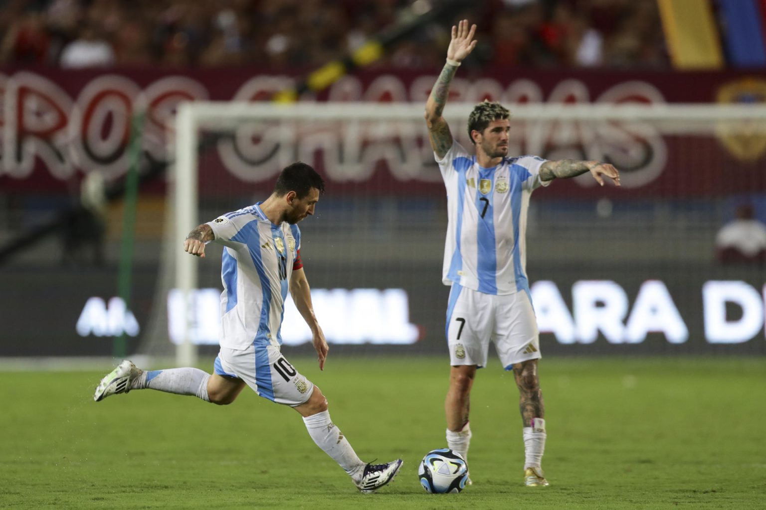 Lionel Messi patea un tiro libre junto a Rodrigo de Paul en el partido de las eliminatorias sudamericanas ante Venezuela en el estadio Monumental de Maturín. EFE/ Ronald Peña R.