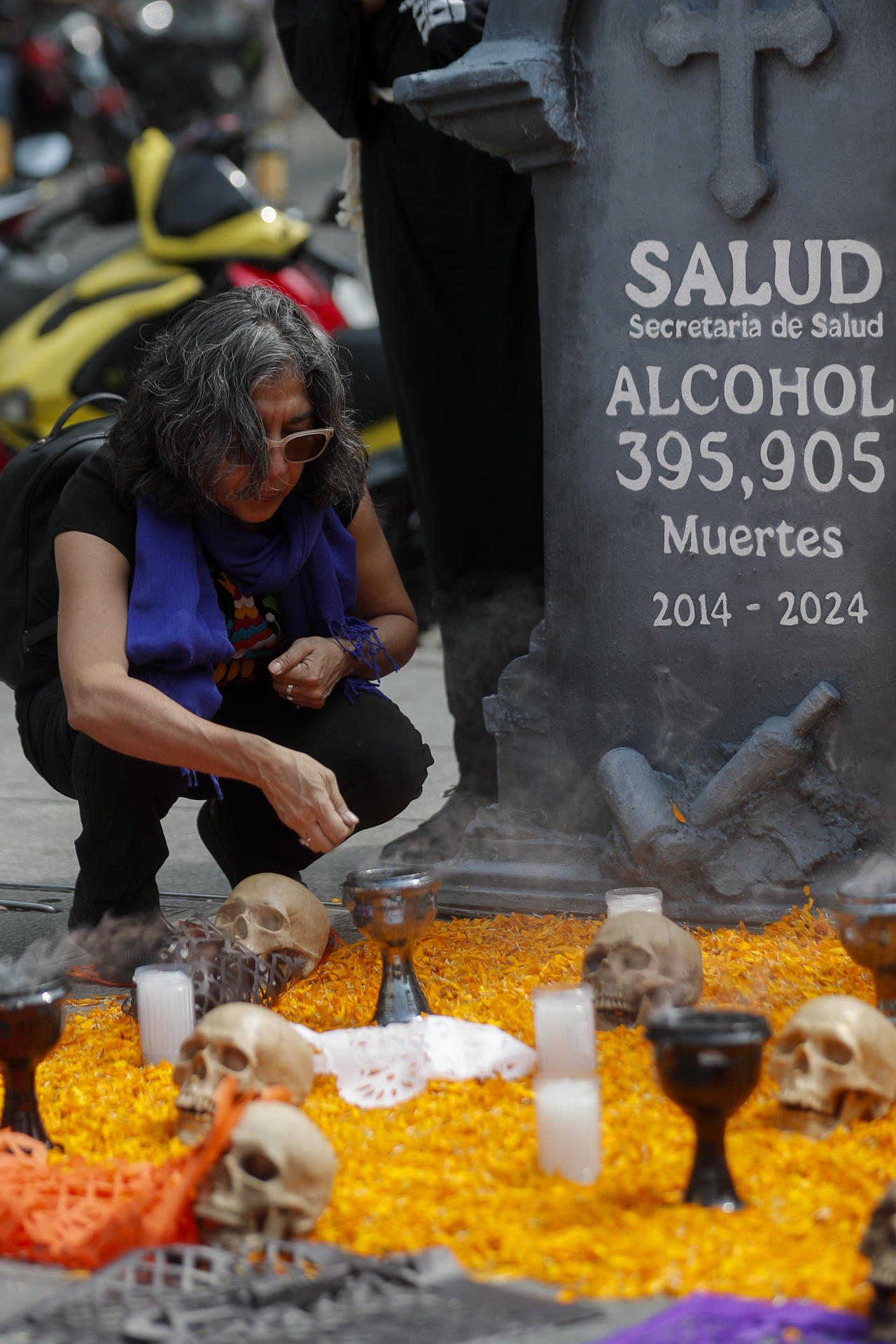 Una mujer se acerca a una ofrenda colocada por organizaciones sociales y con una esquela en la que se lee una presunta cifra de muertes por alcohol entre 2014 y 2024, en un acto de protesta frente a la Secretaría de Salud este jueves, en la Ciudad de México (México). EFE/ Isaac Esquivel
