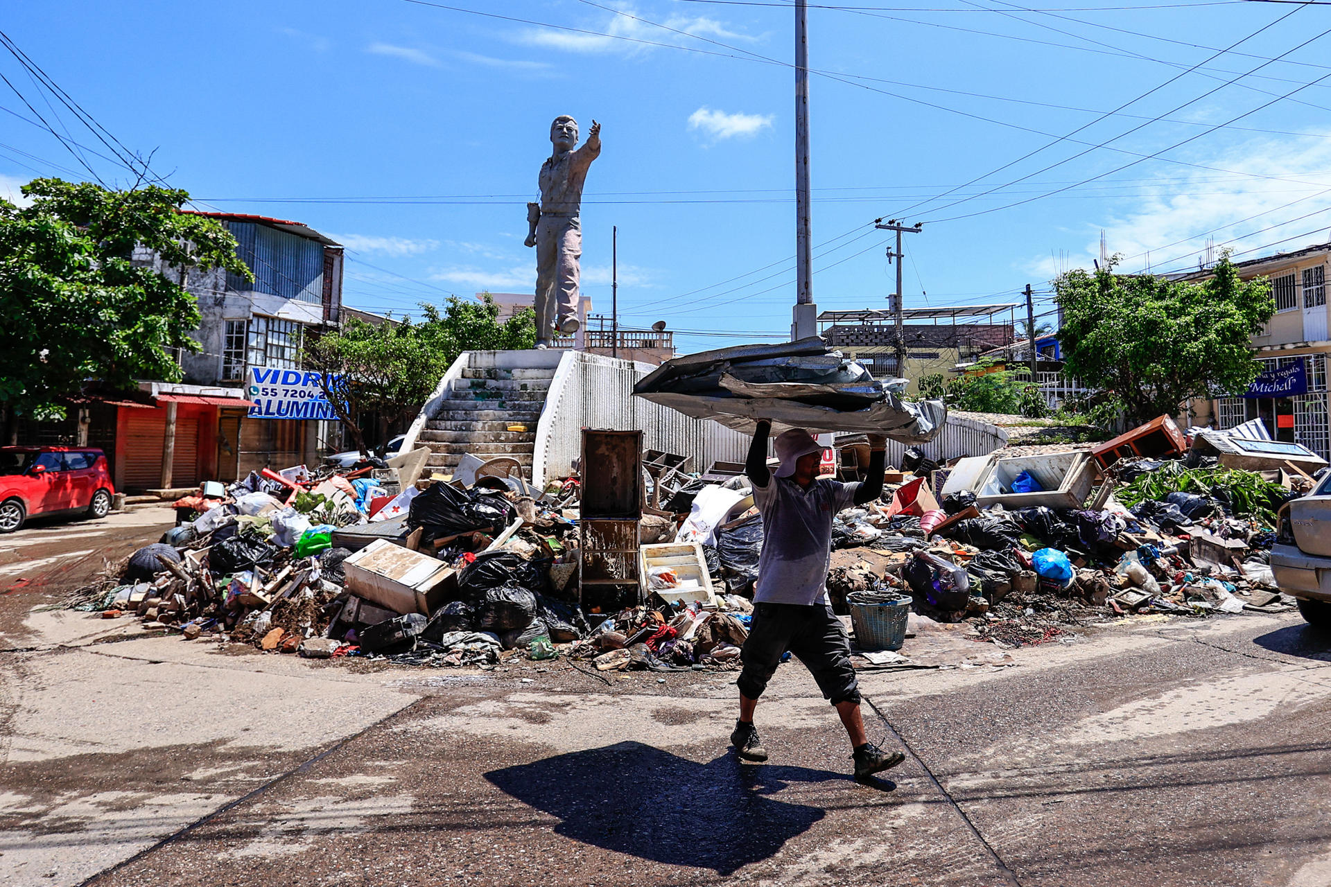 Una persona camina entre basura y enseres domésticos abandonados este lunes en las calles de la unidad habitacional Colosio, una de las más afectadas tras el paso del huracán John, en el balneario de Acapulco (México). EFE/David Guzmán
