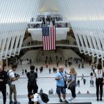 Personas conversan frente a una bandera estadounidenses colgada en el centro de la estación del "Oculos" en el World Trade Center en Nueva York (EE.UU.). Archivo. EFE/Kena Betancur