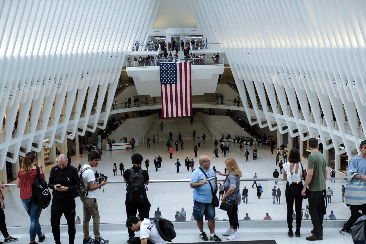 Personas conversan frente a una bandera estadounidenses colgada en el centro de la estación del "Oculos" en el World Trade Center en Nueva York (EE.UU.). Archivo. EFE/Kena Betancur