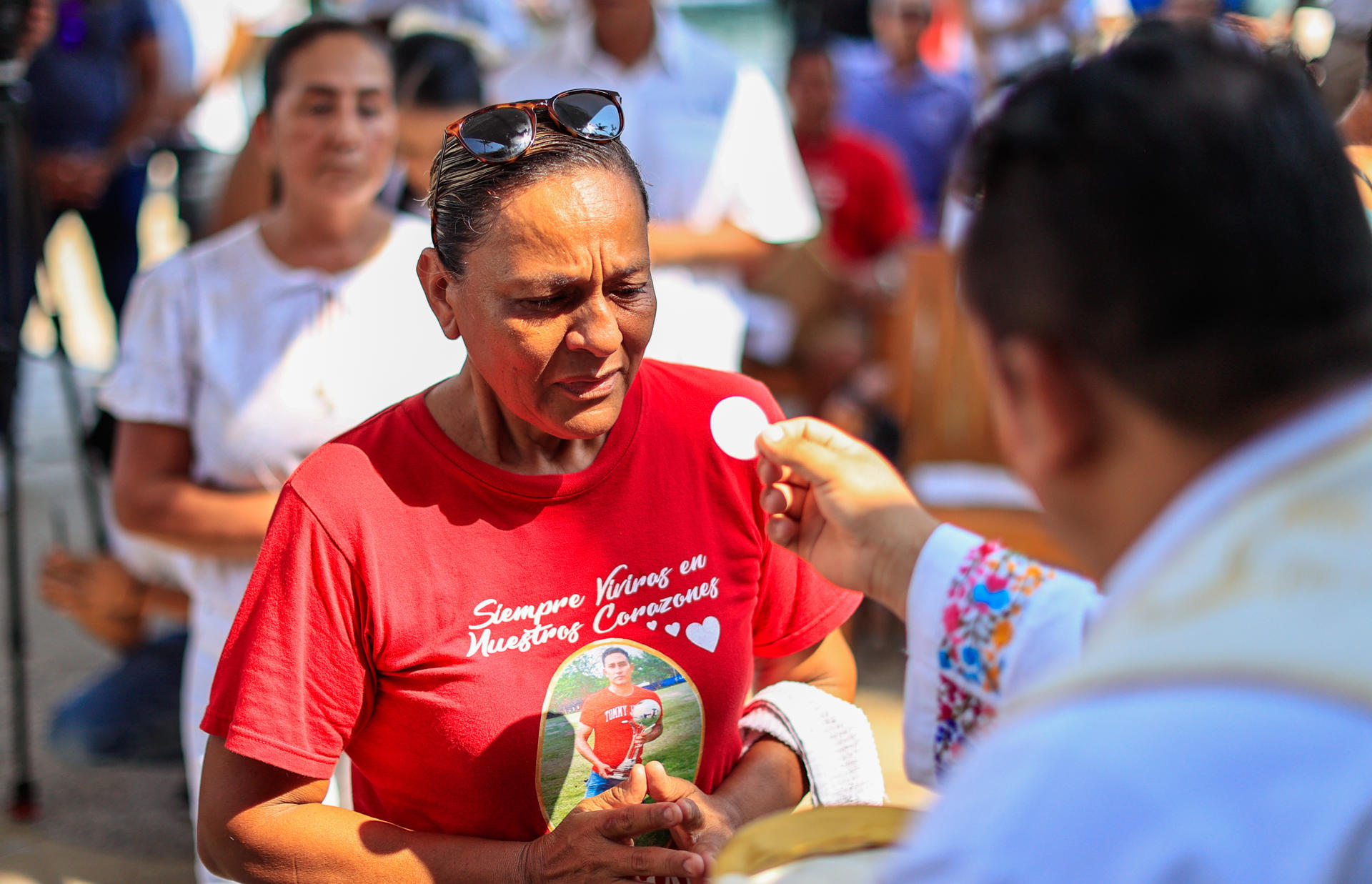 Una mujer recibe la hostia durante una misa de familiares y amigos de personas fallecidas y desaparecidas este viernes, en el balneario de Acapulco en Guerrero (México). EFE/David Guzmán
