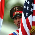 Fotografía de archivo fechada el 21 de marzo de 2016 que muestra un soldado cubano sosteniendo banderas de Cuba y Estados Unidos momentos antes de la llegada del presidente de Estados Unidos Barack Obama, a La Habana (Cuba). EFE. EFE/Alejandro Ernesto