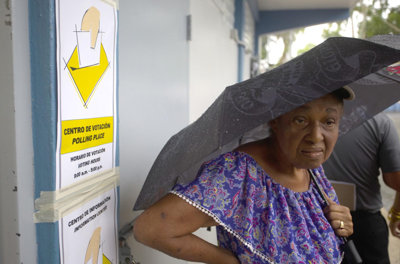 Una mujer se cubre de la lluvia esperando su turno para depositar su voto en un centro de votación en Carolina (Puerto Rico). EFE/Thais Llorca