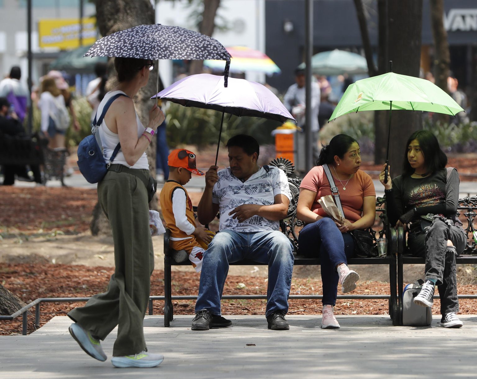 Personas se protegen del sol con sombrillas en el parque de la Alameda Central en la Ciudad de México (México). EFE/Mario Guzmán