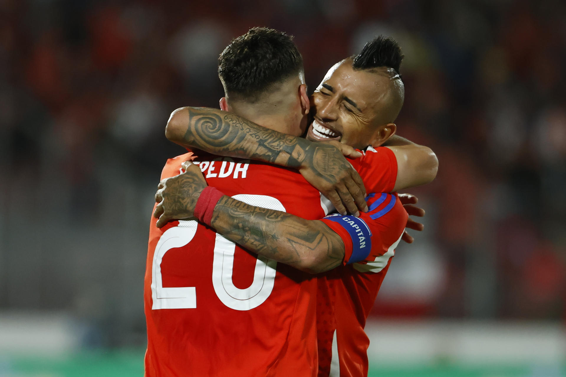 Lucas Cepeda (i), atacante de Chile, fue registrado este martes, 19 de noviembre, al celebrar con su compañero Arturo Vidal un gol que le anotó a Venezuela, durante un partido de la fecha 12 de las eliminatorias sudamericanas al Mundial FIFA de 2026, en el estadio Nacional de Santiago de Chile. EFE/Elvis González
