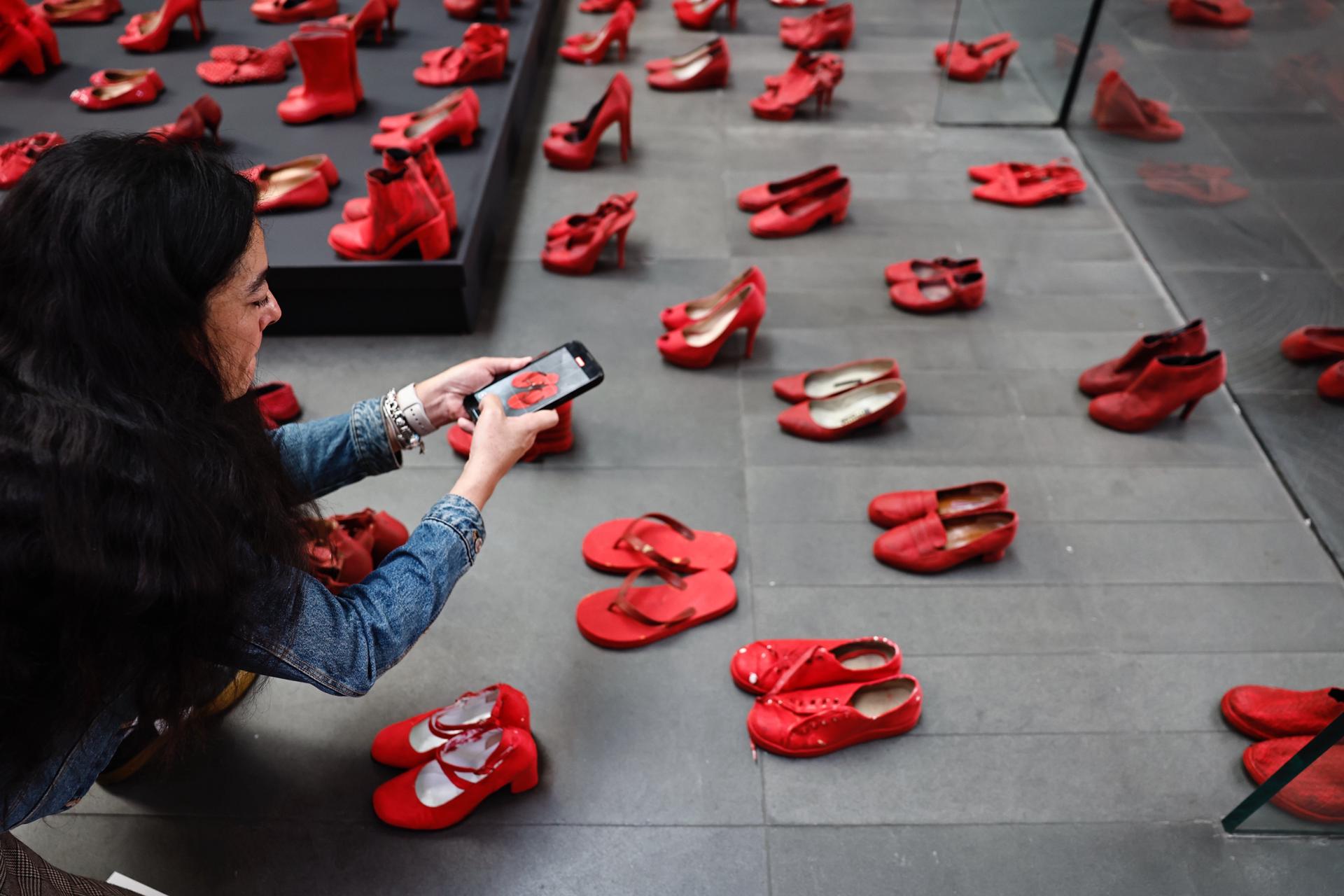 Una mujer toma fotos en la exposición 'Zapatos Rojos' de la artista mexicana Elina Chauvet este jueves, en Ciudad de México (México). EFE/Sáshenka Gutiérrez
