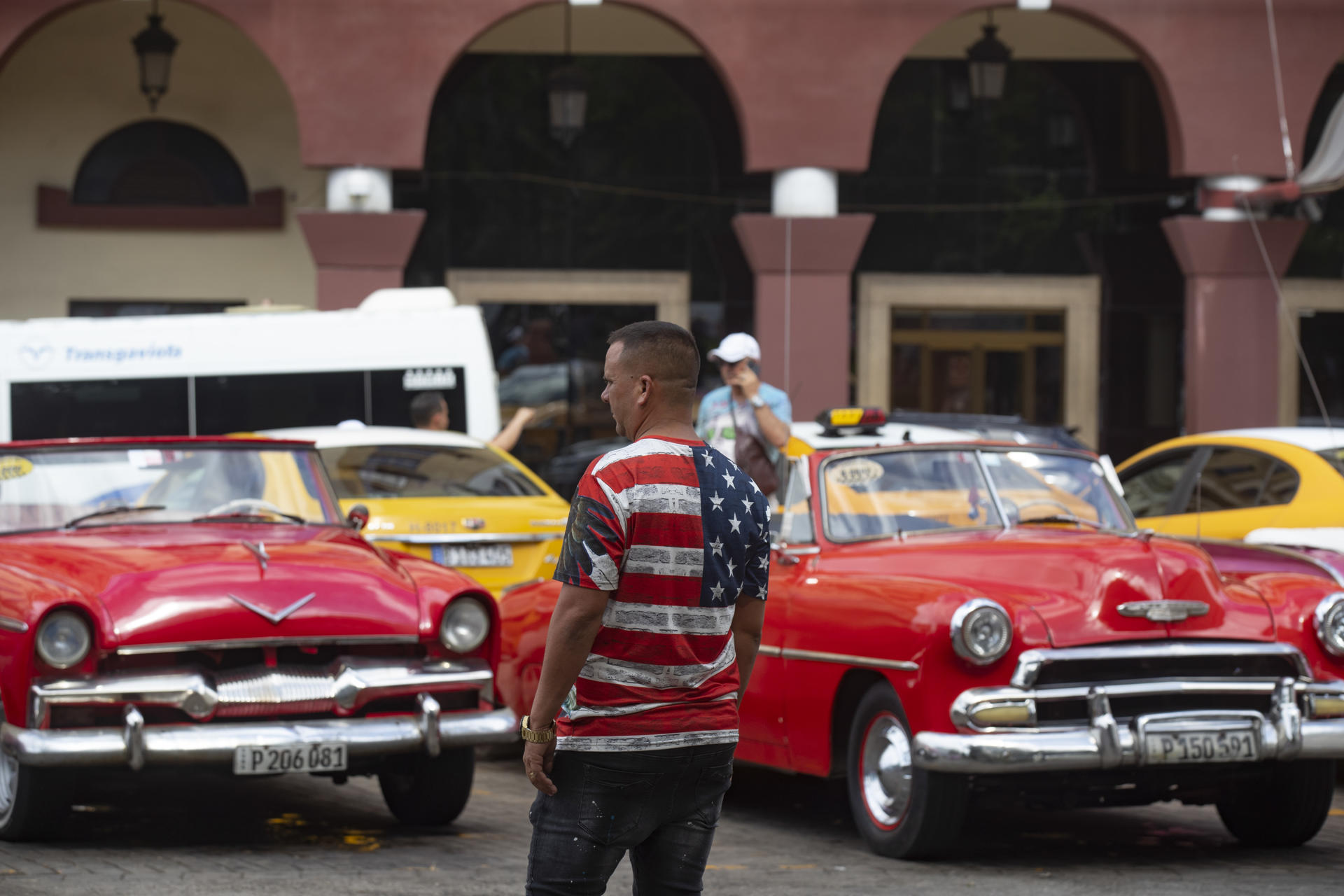 Un hombre con camiseta con la bandera de Estados Unidos observa coches clásicos este viernes, en La Habana (CUBA). EFE/ Yander Zamora
