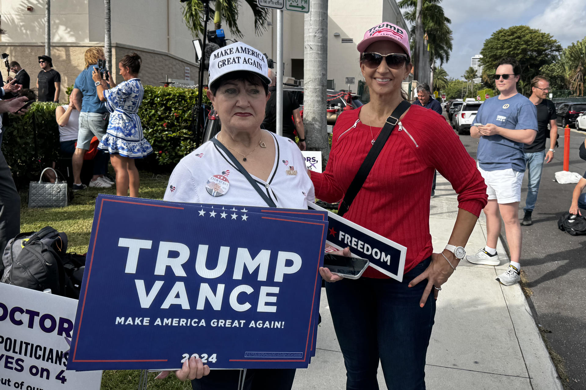 Dos simpatizantes del expresidente y candidato republicano Donald Trump muestran carteles de apoyo al candidato, este martes en Palm Beach, Florida (Estados Unidos). EFE/ Alicia Civita
