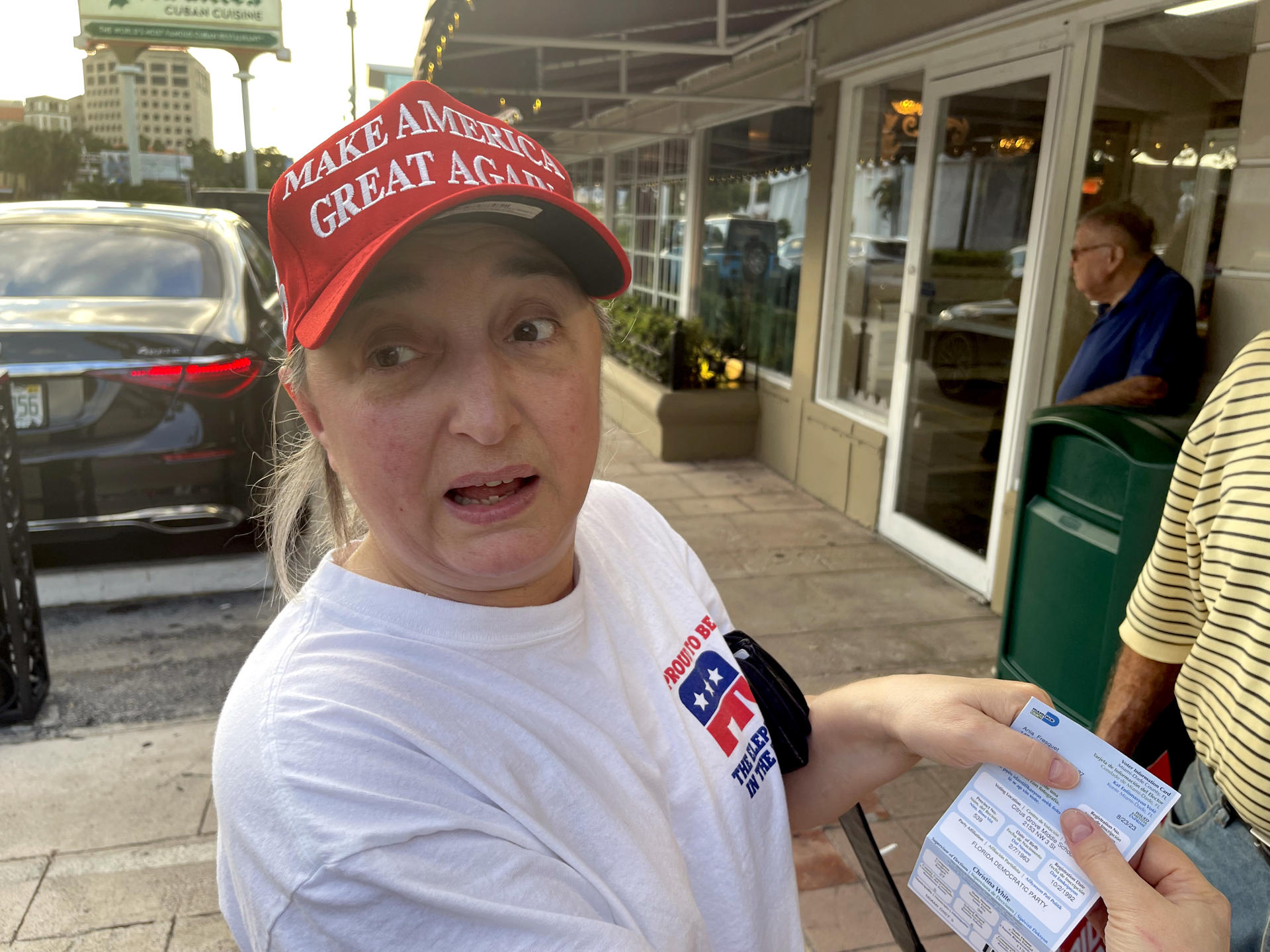 Ania Fresquet, una votante inscrita en la lista demócrata pero que vota por Donald Trump, muestra su tarjeta de votación el lunes 4 de noviembre de 2024 en frente del icónico restaurante Versailles de la Pequeña Habana en Miami, Florida (EE.UU.). EFE/Ana Milena Varón
