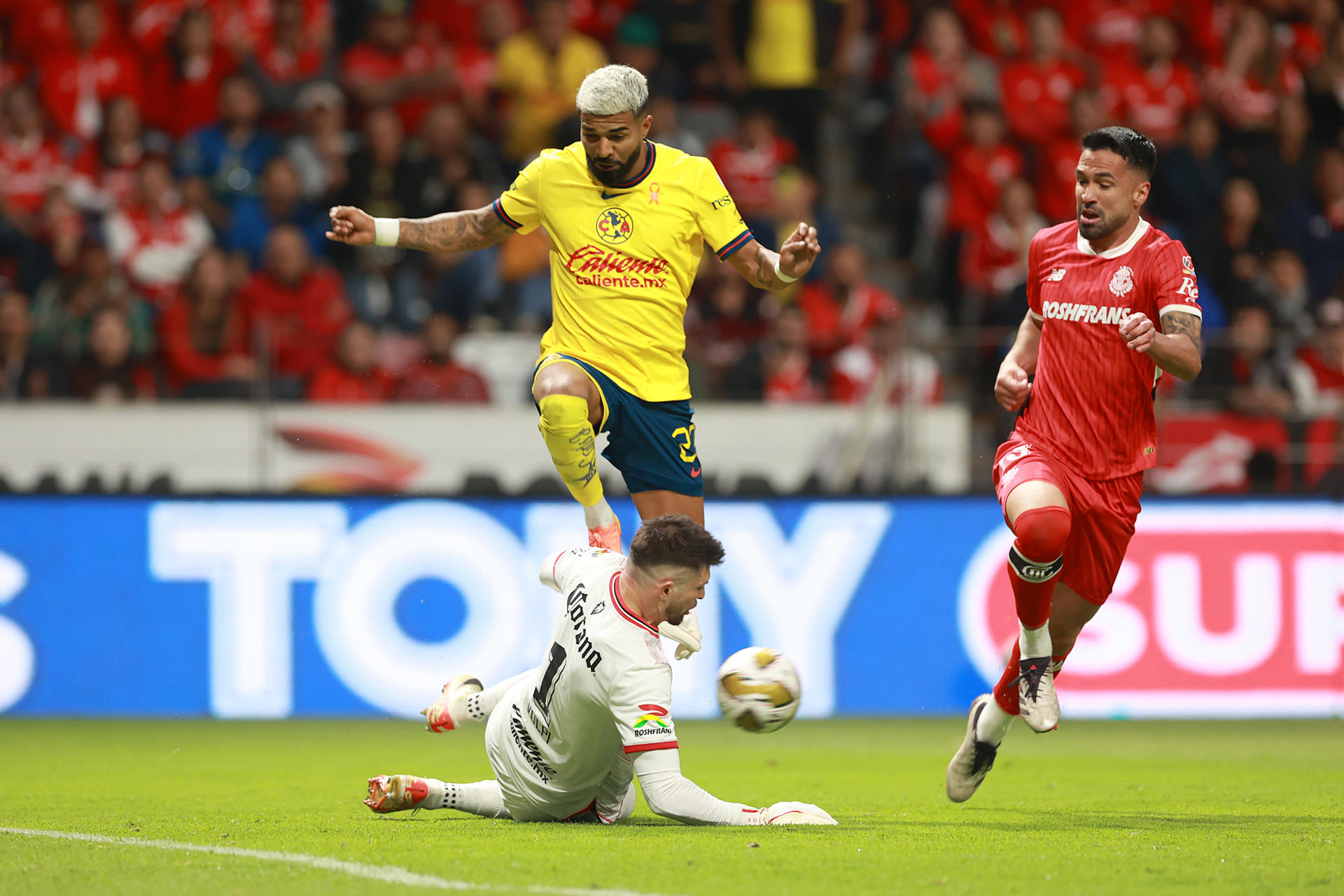 Rodrigo Aguirre (i) de América disputa un balón con Tiago Volpi (abajo) y Luan García de Toluca este sábado, durante un partido de vuelta de los cuartos de final del torneo Apertura 2024 de la Liga MX. EFE/ Alex Cruz
