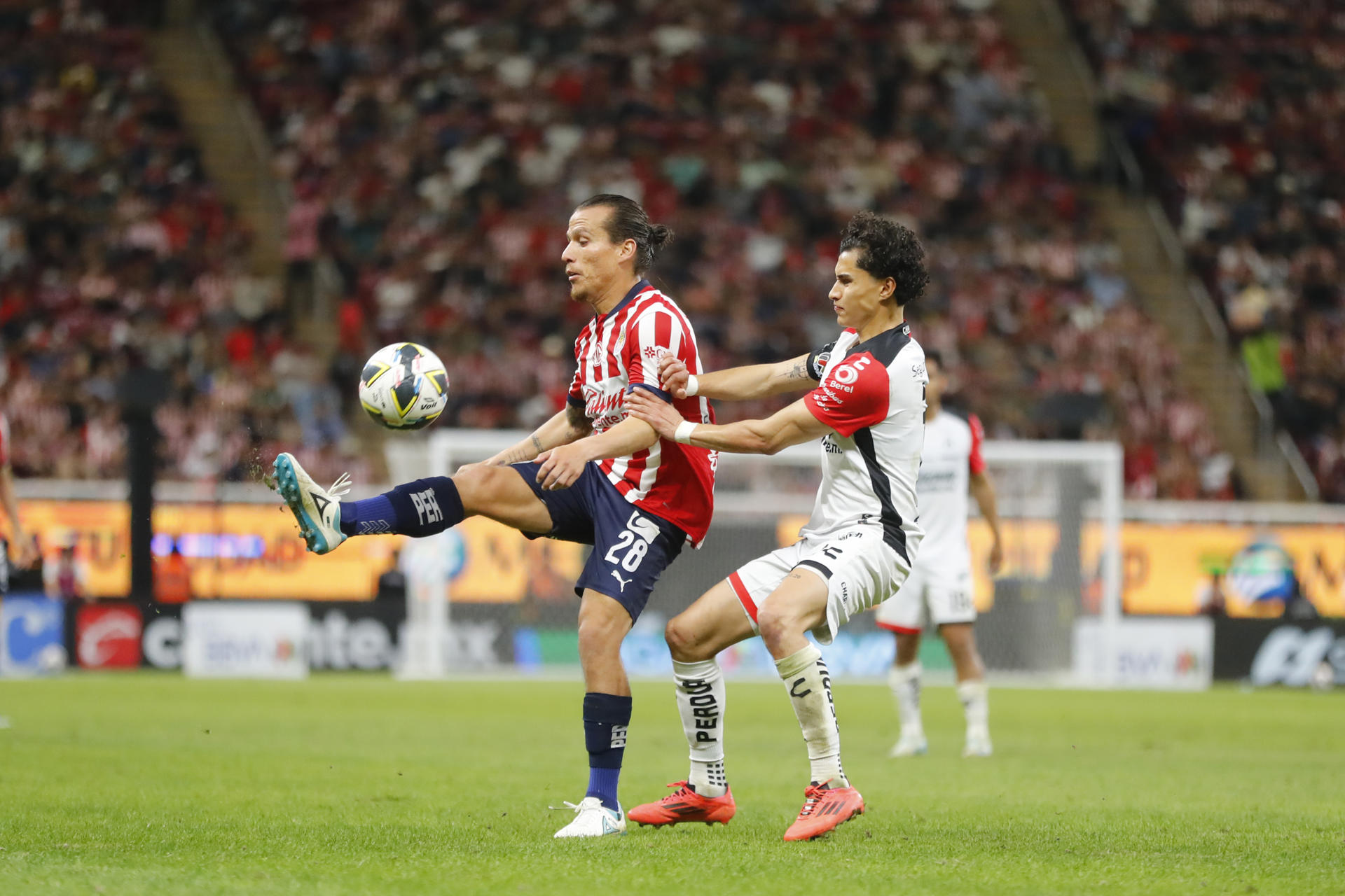 Fernando González (i) de Guadalajara disputa el balón con Jeremy Márquez (d) de Atlas este jueves, durante un partido de reclasificación del torneo Apertura mexicano jugado en Guadalajara, Jalisco. EFE/ Francisco Guasco
