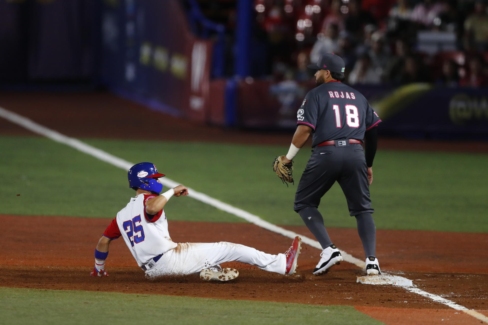 Ezequiel Pagan (i) de Puerto Rico se desliza en busca de la primera base ante José Rojas (d) de México este domingo, en juego de la segunda jornada de la serie Premier 12 de béisbol, que transcurre en Guadalajara. EFE/Francisco Guasco
