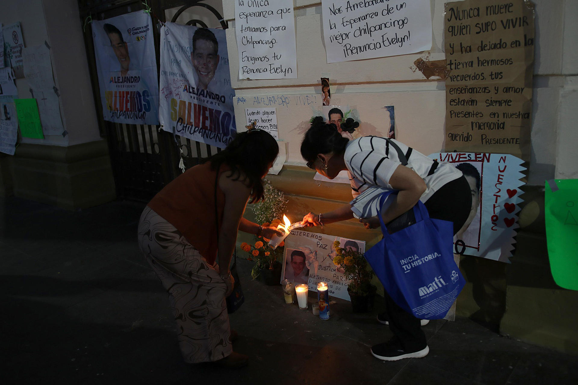 Dos mujeres prenden una veladora en un altar, durante una marcha para exigir justicia por el asesinato del alcalde Alejandro Arcos Catalán, este viernes en Chilpancingo, en el estado de Guerrero (México). EFE/José Luis de la Cruz
