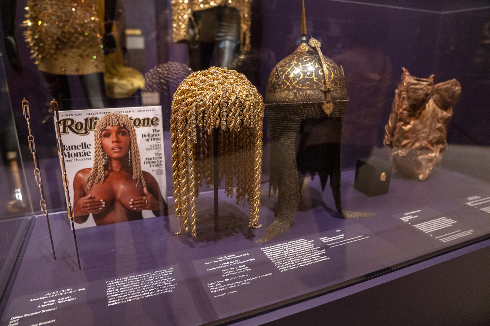 Fotografía de un casco y peluca de oro diseñadas por Jacob Arobo, junto a un ejemplar de la revista Rolling Stones donde aparece la cantante Janelle Monáe, durante la exposición 'Solid Gold' ('Oro sólido') este miércoles, en el Museo de Brooklyn en Nueva York (Estados Unidos). EFE/ Ángel Colmenares
