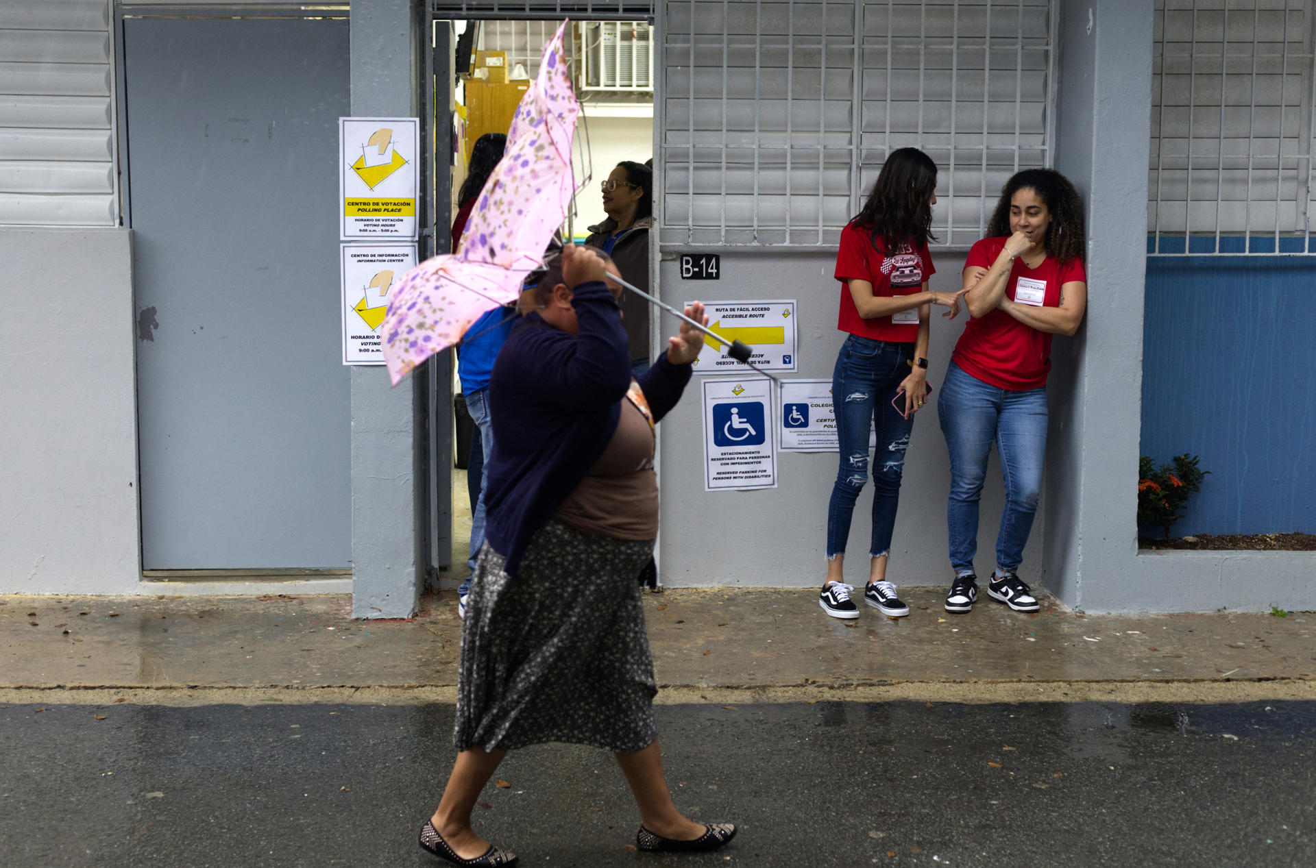 Una persona camina frente a dos voluntarias de un centro de votación este martes en Carolina (Puerto Rico). EFE/Thais Llorca
