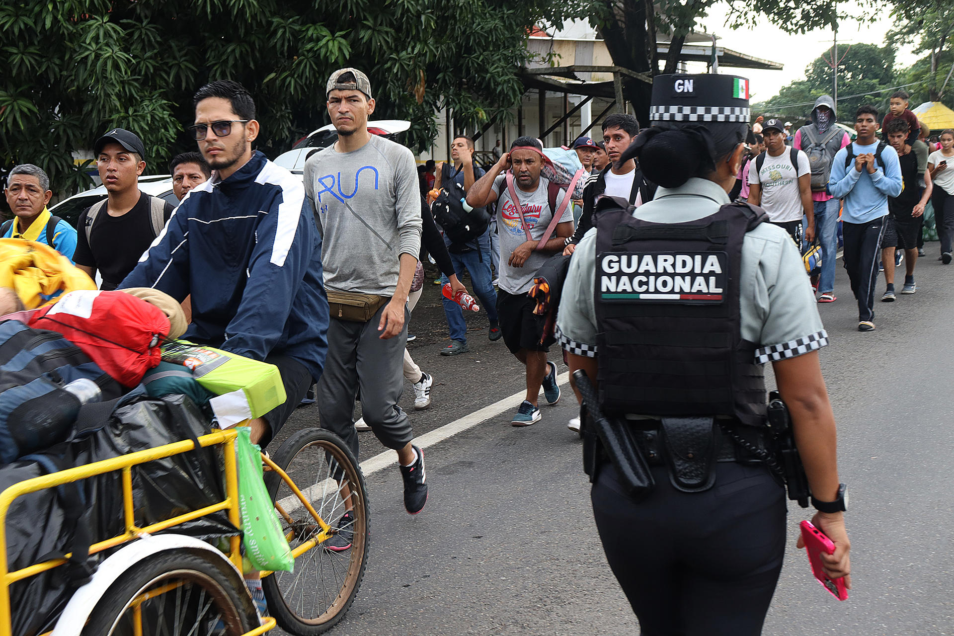 Una integrante de la Guardia Nacional resguarda una caravana de migrantes que caminan hacia la frontera con Estados Unidos este miércoles, en el municipio de Tapachula en el estado de Chiapas (México). EFE/ Juan Manuel Blanco
