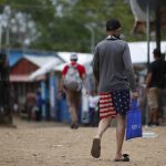 Un migrante camina vistiendo una prenda impresa con la bandera de los Estados Unidos en la Estación Temporal de Recepción Migratoria (ETRM), en Lajas Blancas, Darién (Panamá). EFE/Bienvenido Velasco