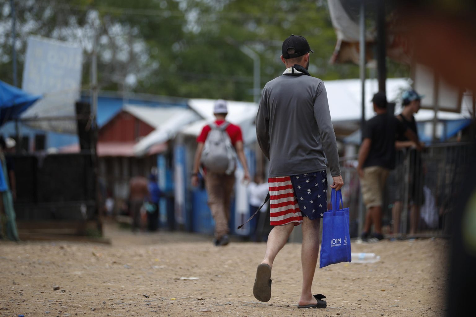 Un migrante camina vistiendo una prenda impresa con la bandera de los Estados Unidos en la Estación Temporal de Recepción Migratoria (ETRM), en Lajas Blancas, Darién (Panamá). EFE/Bienvenido Velasco