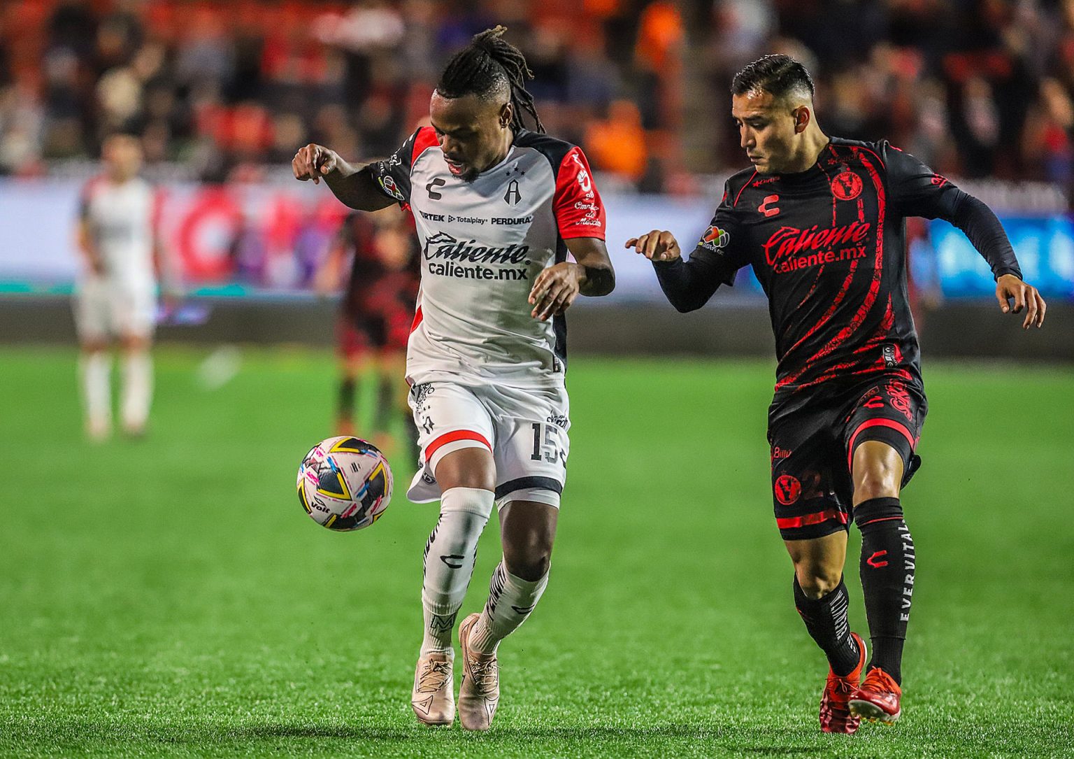 Fernando Monarrez (d) de Tijuana disputa el balón con Jhon Murillo (i) de Atlas en el partido jugado este domingo en el estadio Caliente de la ciudad de Tijuana que clasificó a los locales a los cuartos de final del torneo Apertura mexicano. EFE/ Alejandro Zepeda