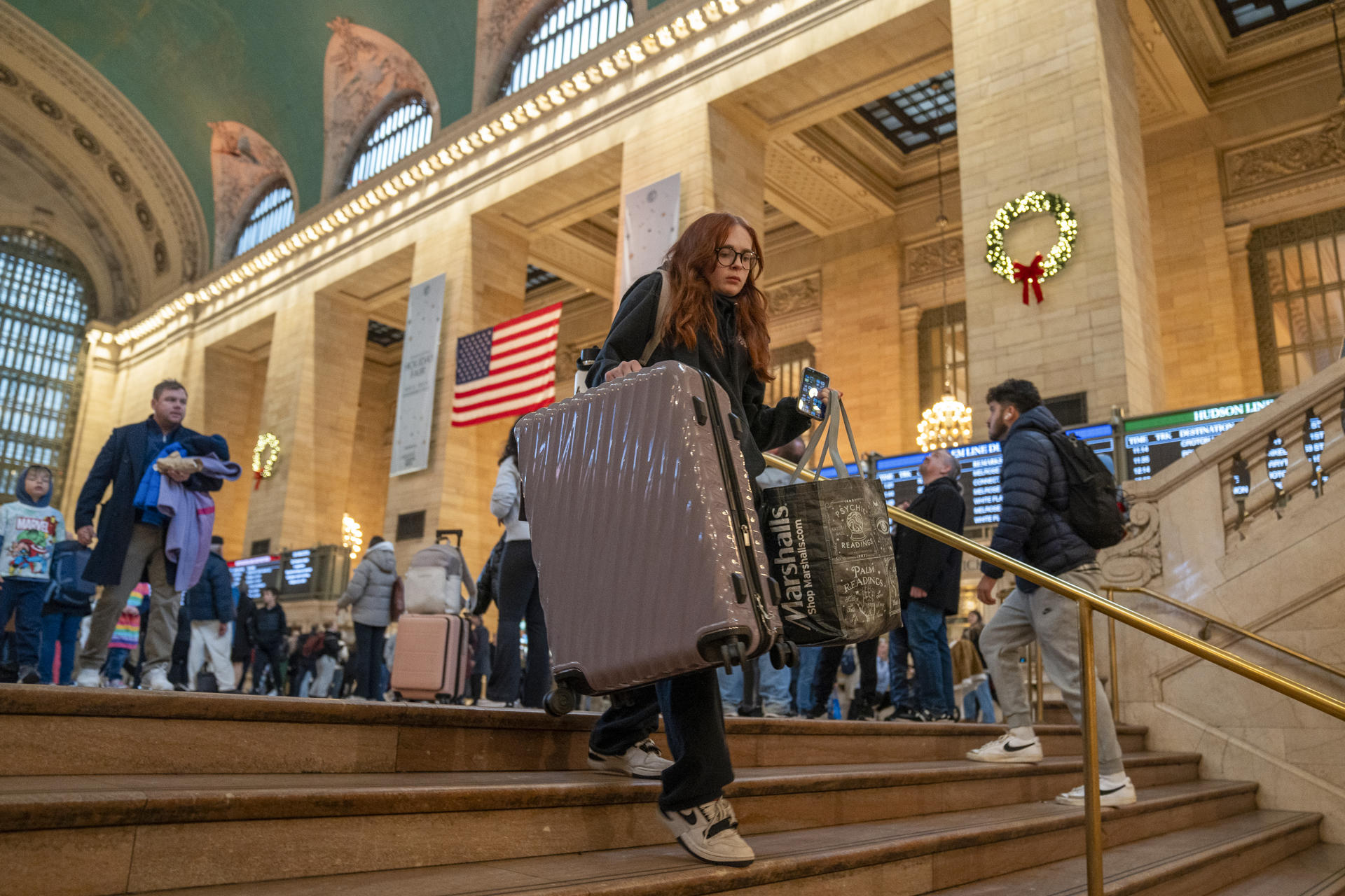 Una mujer baja las escaleras con maletas este miércoles para tomar un tren en la estación Gran Central de Nueva York (EE.UU). EFE/Ángel Colmenares
