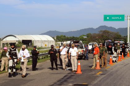 Personal del Instituto Nacional de Migración (INM) y de la Guardia Nacional (GN) bloquean una carretera ante el avance de una caravana de migrantes que caminan hacia la frontera con Estados Unidos este jueves, en el municipio de Huiixtla, en el estado de Chiapas (México). EFE/ Juan Manuel Blanco