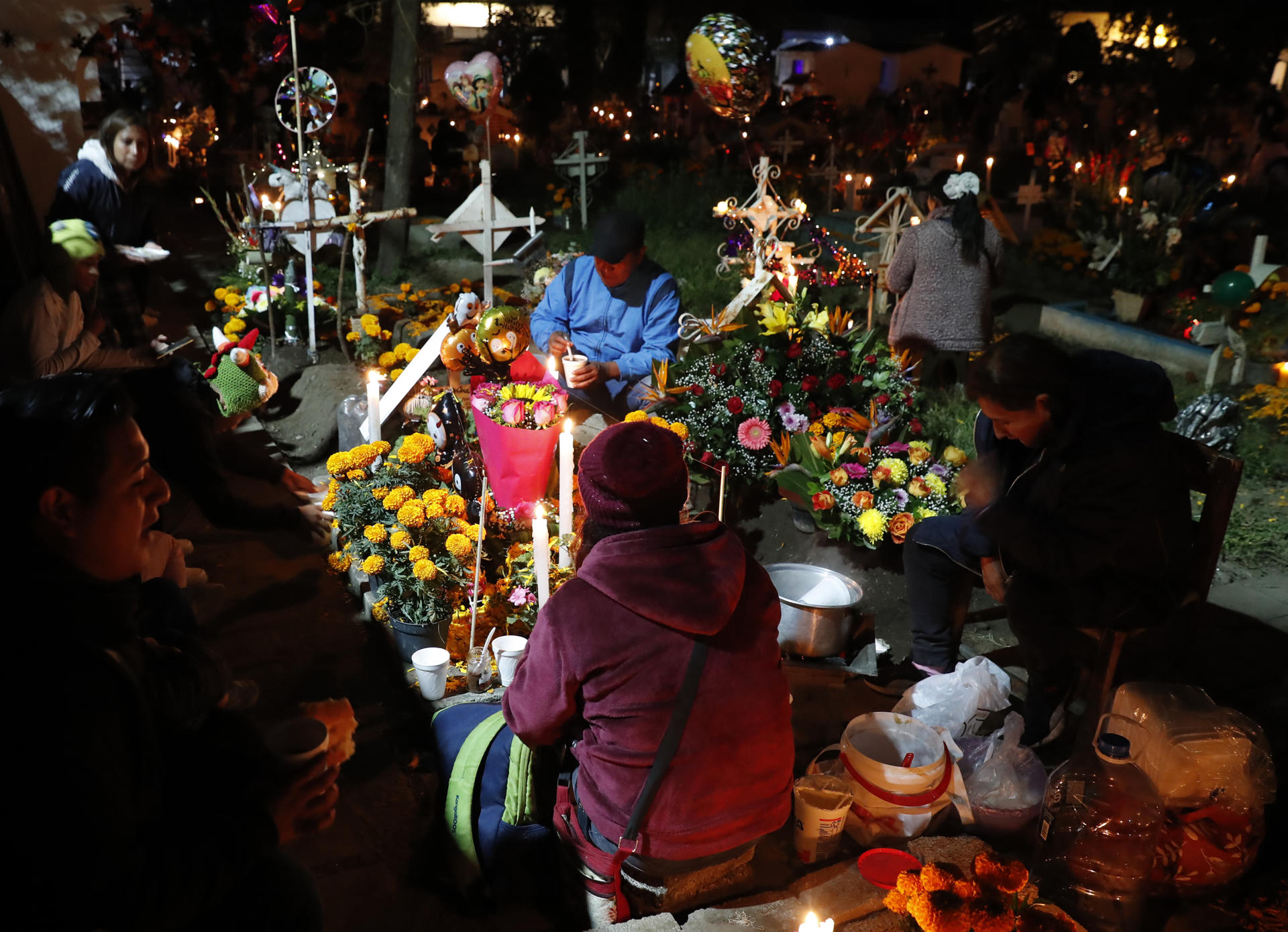 Familiares y amigos visitan a sus fieles difuntos la madrugada de este viernes en el panteón comunal San Gregorio Atlapulco, en la Ciudad de México (México). EFE/Mario Guzmán
