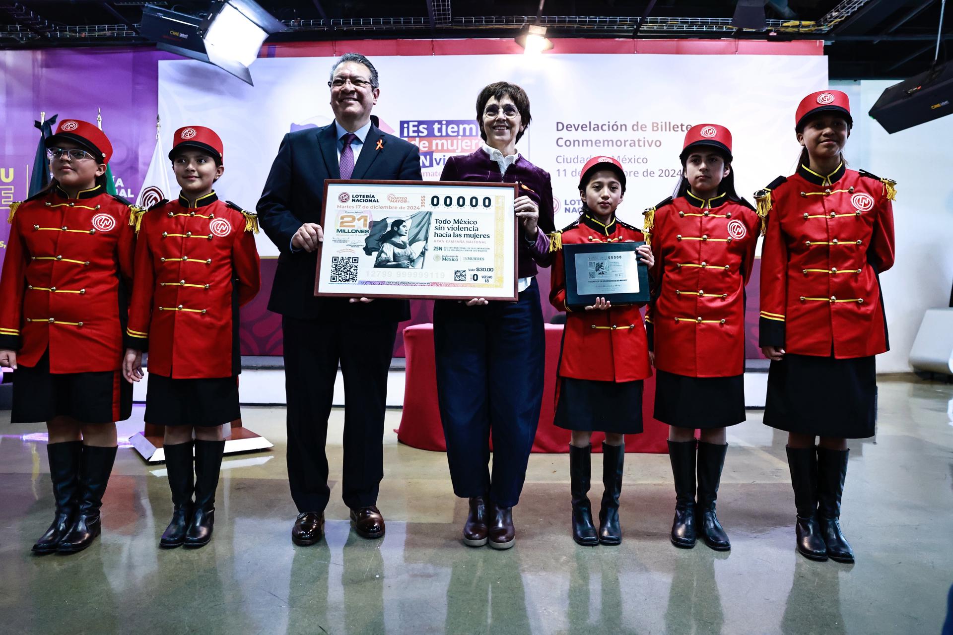 El director general de la Lotería Nacional, Marco Antonio Mena Rodríguez (3-i) y la directora general de la Política Nacional de Igualdad del Instituto Nacional de las Mujeres, Marta Ferreyra (c), posan durante la develación del billete de lotería 'Es tiempo de mujeres' este miércoles en Ciudad de México (México). EFE/Sáshenka Gutiérrez
