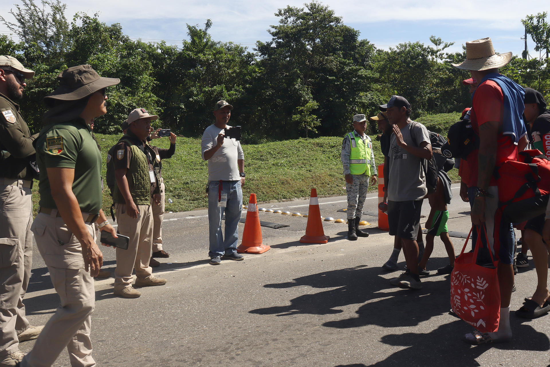 Personal del Instituto Nacional de Migración (INM) hablan con migrantes este martes, en el municipio de Huixtla en el estado de Chiapas (México). EFE/Juan Manuel Blanco
