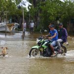 Imagen de archivo de dos personas que se movilizan en motocicleta por una calle inundada tras el paso del huracán Milton, en Celestún (México). EFE/ Lorenzo Hernández