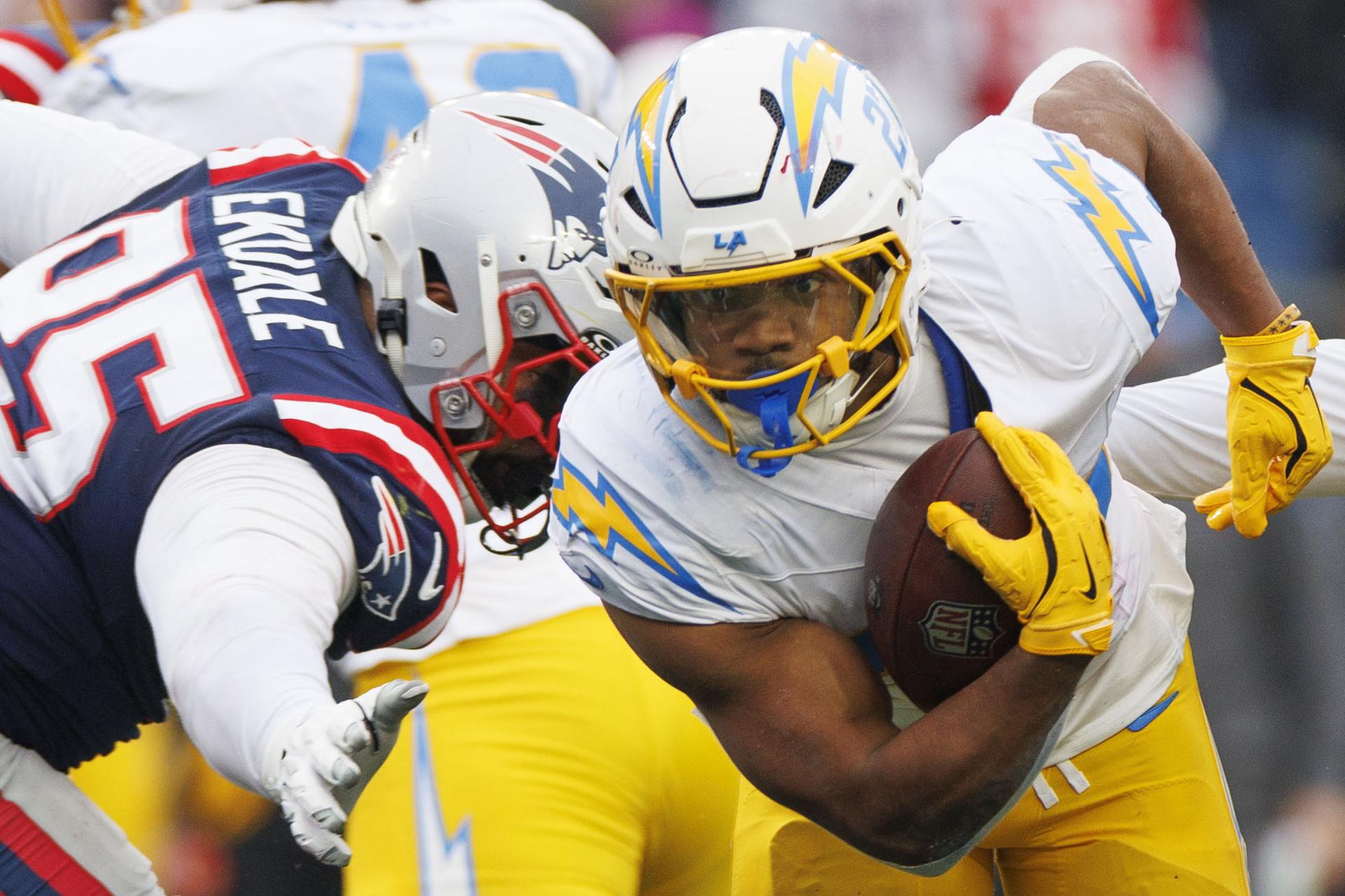 J.K. Dobbins (d), corredor de Los Ángeles Chargers, fue registrado este sábado, 28 de diciembre, al disputar un balón con Daniel Ekuale (i), defensa de los New England Patriots, durante un partido de la NFL, en el Gillette Stadium de Foxborough (Massachusetts, EE.UU.) EFE/CJ Gunther
