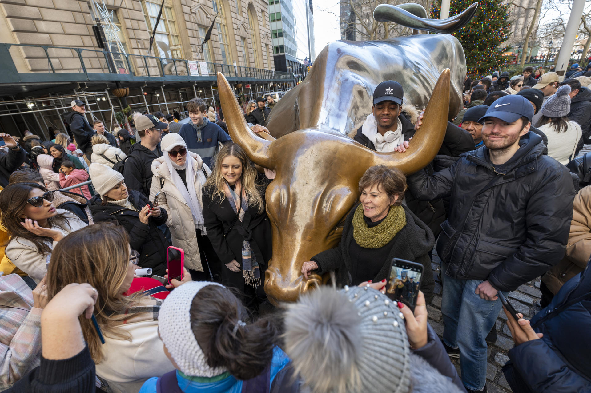 Varias personas se toman una fotografía con la escultura del toro de Wall Street, este lunes en Nueva York (Estados Unidos). EFE/ Angel Colmenares
