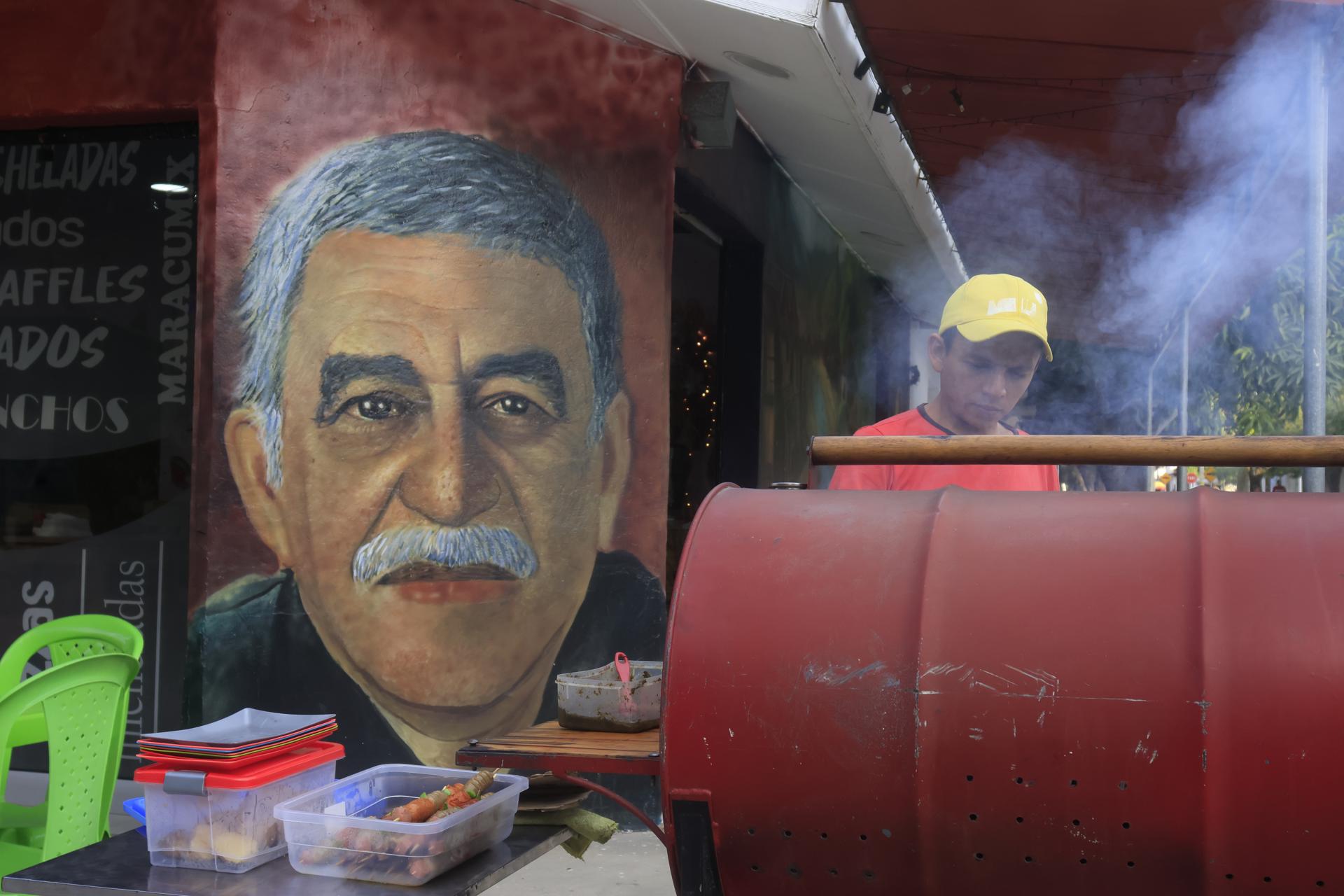 Un hombre cocina frente a un mural con la imagen del escritor Gabriel García Márquez, este miércoles en Aracataca (Colombia). EFE/ Ricardo Maldonado Rozo
