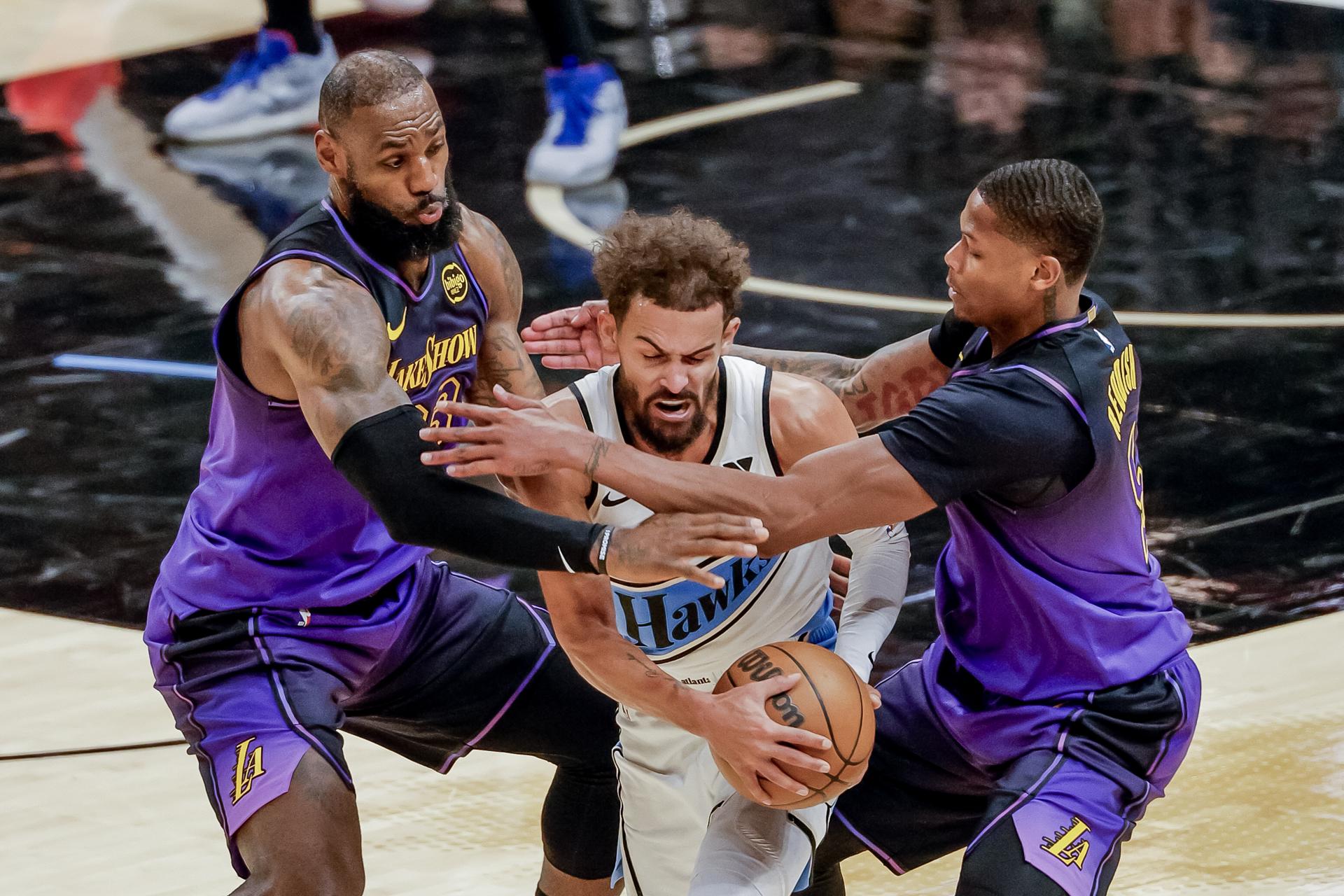 El escolta de los Hawks, Trae Young (c), recibe la presión de los aleros de Los Angeles Lakers, LeBron James (i) y Cam Reddish (d), durante el juego que este viernes ganó la franquicia de Atlanta por 134-132. EFE/EPA/ERIK S. LESSER FUERA DE SHUTTERSTOCK
