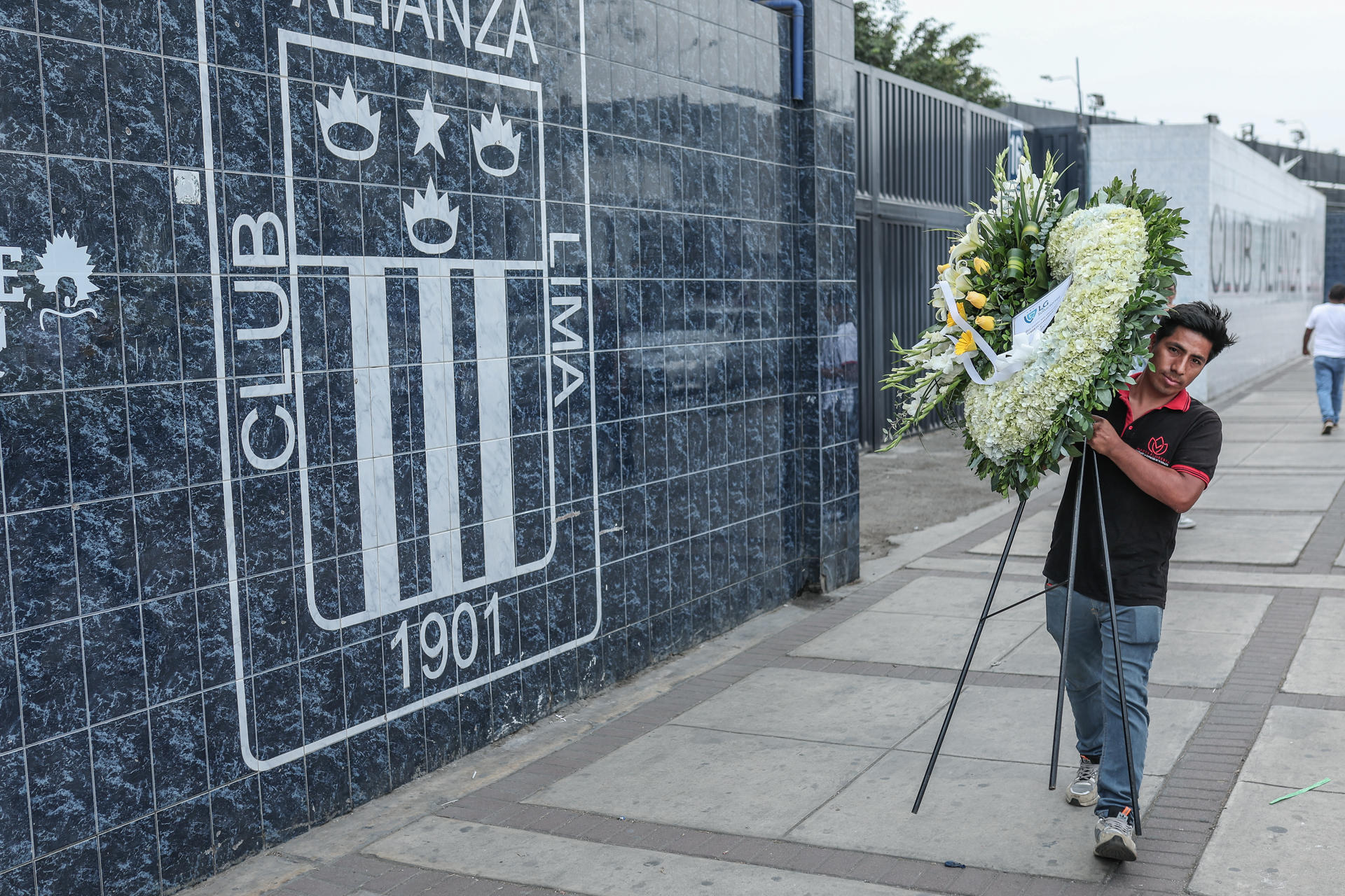 Un hombre carga un ramo de flores en honor al exfubolista peruano Hugo 'Cholo' Sotil afuera del estadio Alejandro Villanueva del club Alianza Lima en Lima (Perú). EFE/ Aldair Mejía
