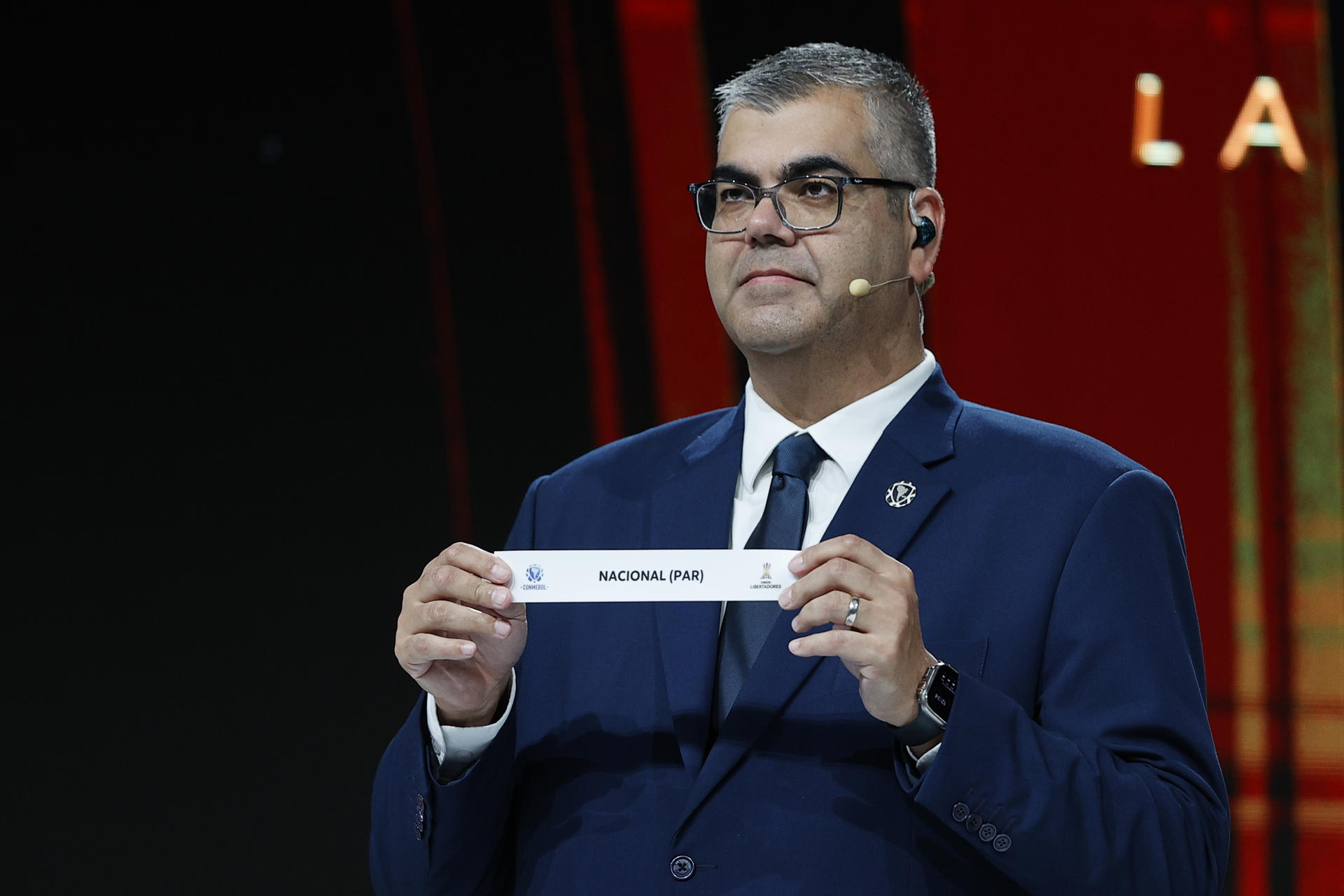 El director de competiciones de clubes de la Conmebol, Frederico Nantes, sostiene el nombre del equipo paraguayo Nacional en el sorteo de la fase preliminar de la Copa Libertadores 2025. EFE/ Juan Pablo Pino
