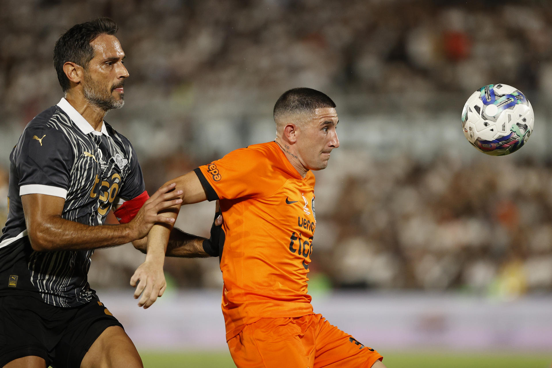 El capitán del club Libertad, Roque Santa Cruz (i), ejerce cerrada marca cobre Facundo Zabala, de Olimpia, durante el partido por la Supercopa de Paraguay que conquistó su equipo al imponerse por 2-1 en el estadio asunceno Defensores del Chaco. EFE/ Juan Pablo Pino
