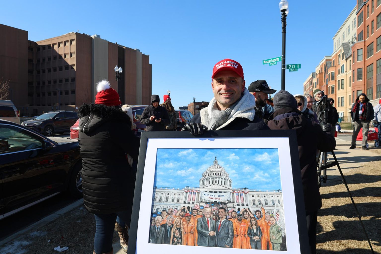 Samuel Lazar uno de los condenados por participar en el asalto al Capitolio del 6 de enero de 2021, puesto en libertad en septiembre de 2023, sostiene un cuadro este miércoles, frente al Centro de Detención en Washington (Estados Unidos). EFE/ Esteban Capdepon