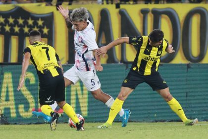 Elian Irala (c) de San Lorenzo busca eludir la marca de dos rivales de Peñarol este jueves, en el partido de pretemporada correspondiente a la Serie Río de la Plata, que ganó el conjunto argentino por 1-2 en estadio Campeón del Siglo de Montevideo. EFE/ Gastón Britos