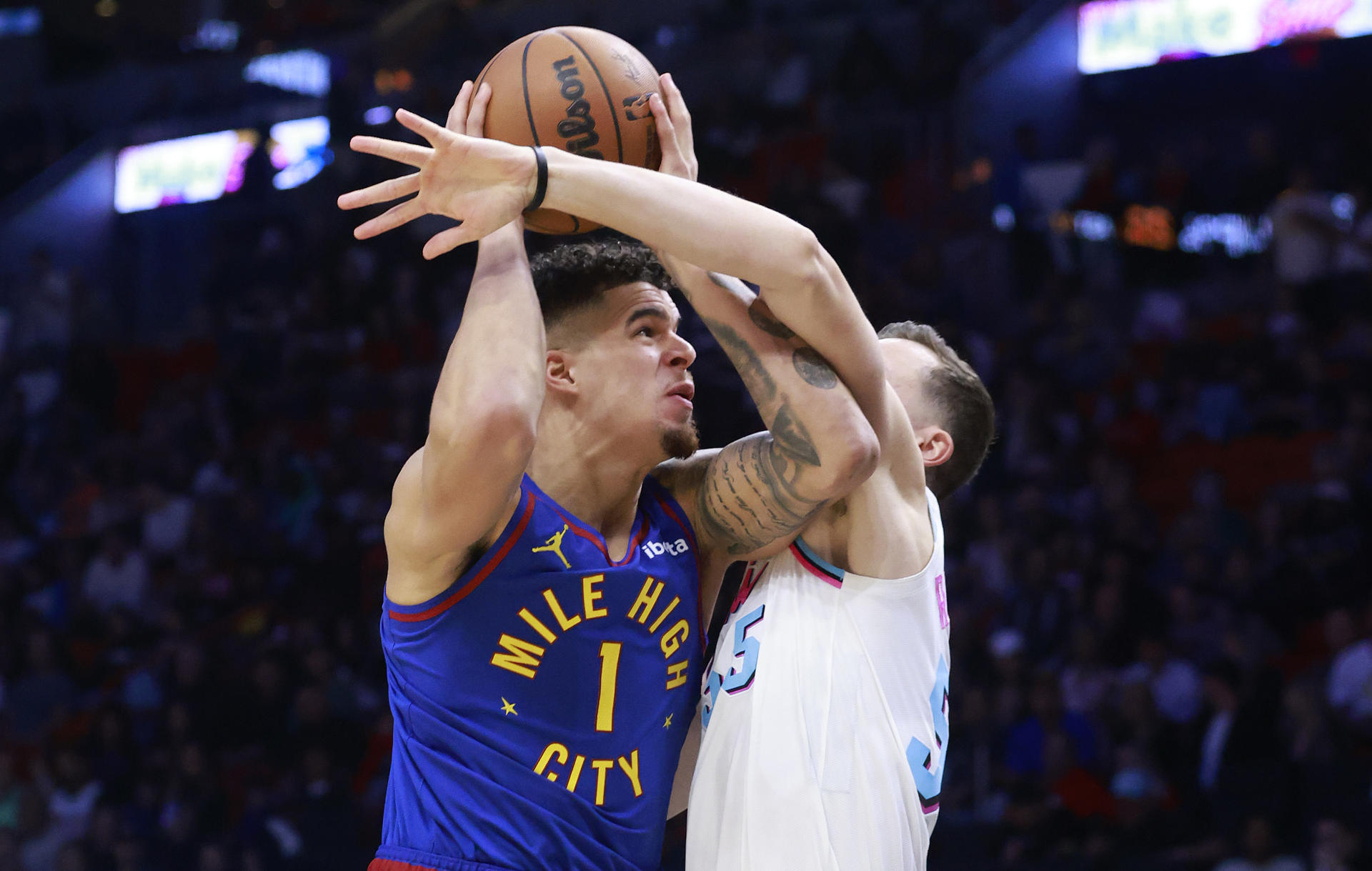 Michael Porter Jr. de Denver Nuggets (i) disputa un balón con Duncan Robinson de Miami Heat este viernes, durante un partido en el Kaseya Center en Miami (Florida), que los locales perdieron sin atenuantes por 113-133.. EFE/ Rhona Wise
