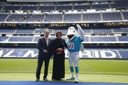 Brett Gosper, director de la NFL en Europa y Asia-Pacífico y Pri Shumate, vicepresidenta de los Miami Dolphins, en el césped del Santiago Bernabéu con la mascota del equipo, durante el acto celebrado este viernes. EFE/ Blanca Millez