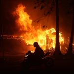 Una persona conduce su motocicleta junto a una casa en llamas durante los incendios en Palisades , California, Estados Unidos. EFE/ Allison Dinner