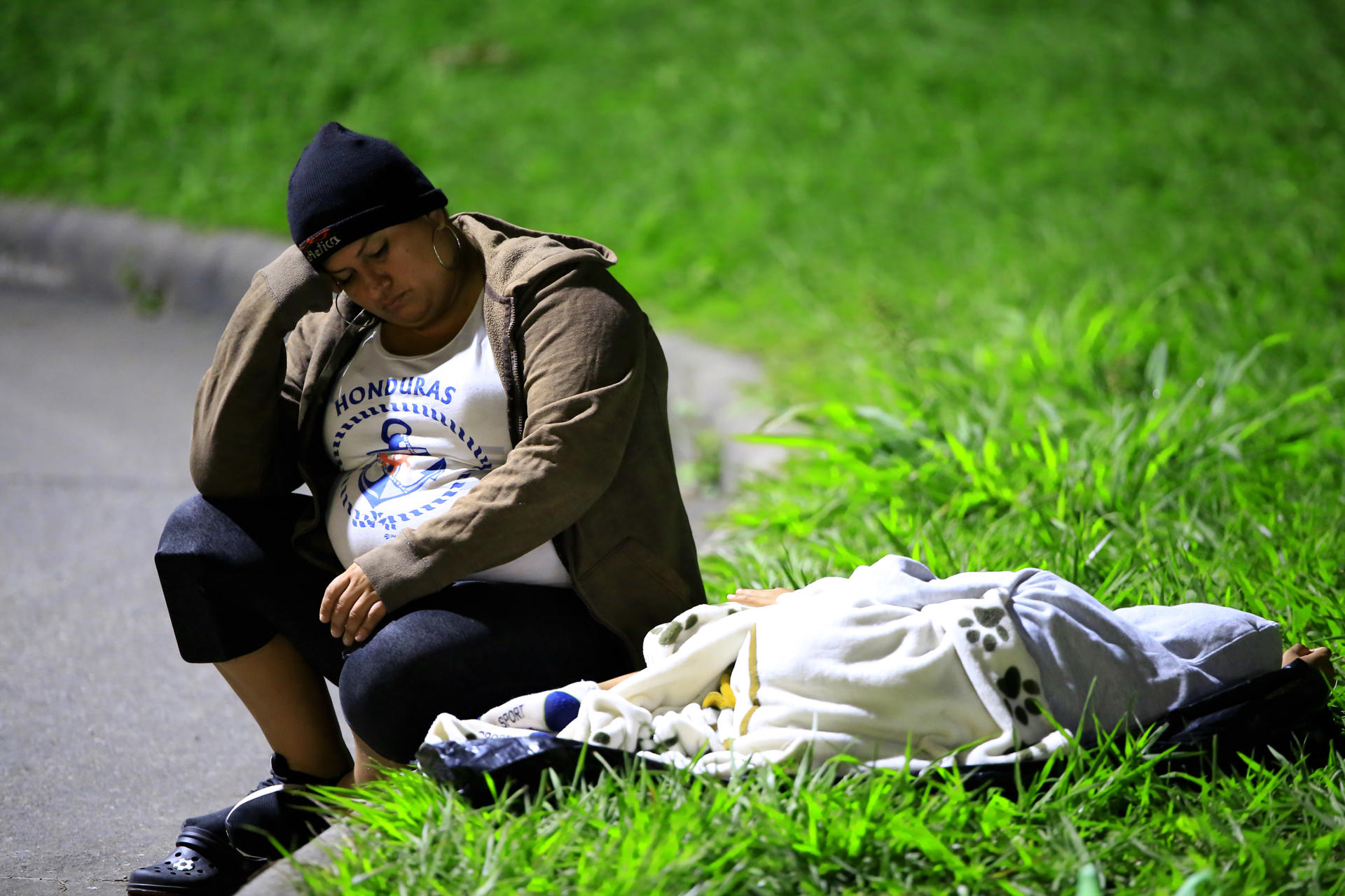 Una mujer descansa junto a su hija antes de salir en una caravana de migrantes con rumbo a la frontera de Guatemala este lunes, en San Pedro Sula (Honduras). EFE/ Jose Valle
