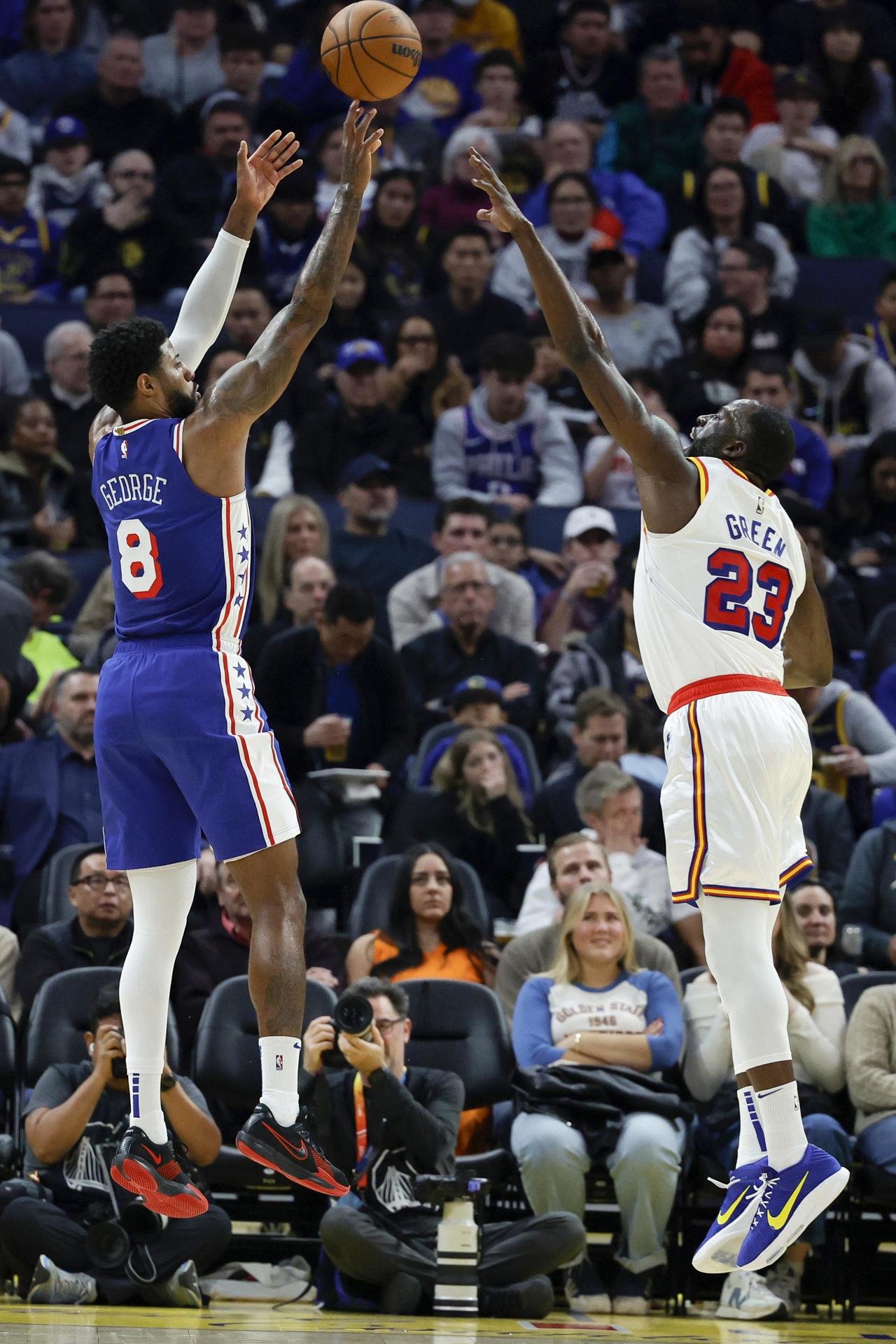 El alero de los Philadelphia 76ers, Paul George, lanza un tiro de dos puntos sobre el alero de los Warriors, Draymond Green, durante el partido ganado este jueves por Golden State (139-105) en San Francisco (California). EFE/EPA/JOHN G. MABANGLO
